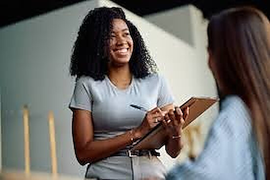 A smiling care coordinator with a clipboard listening closely during a visit